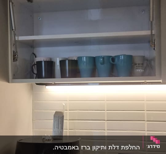ארון מטבח פתוח עם כוסות, מכונת קפה על השיש